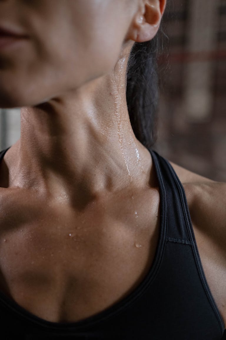 Close-up of a fit woman in activewear glistening with sweat, showcasing toned muscles.
